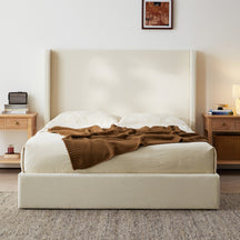 upholstered wingback bed with brown blanket in bedroom
