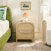 Wooden nightstand with lamp and mug in a bedroom setting