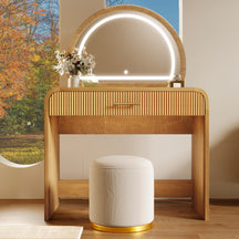 Wooden vanity table with illuminated mirror and white stool in a room with autumn foliage outside.