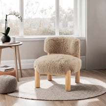Beige furry chair in a room with a window and small table.