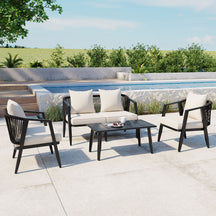Outdoor patio set with black frames and white cushions by a poolside.