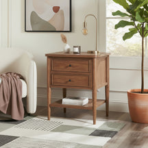 Wooden nightstand with lamp and books in a bedroom setting